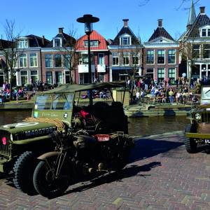 Colonne oude legervoertuigen in en door centrum van Stiens